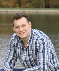 A man wearing a plaid shirt, smiling. 